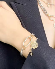 Gold and silver chain bracelet with star and evil eye pendants worn by a person