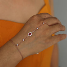 Woman wearing a delicate finger and wrist chain bracelet with a  ruby