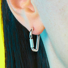 Close-up of a person wearing a silver carabiner earring